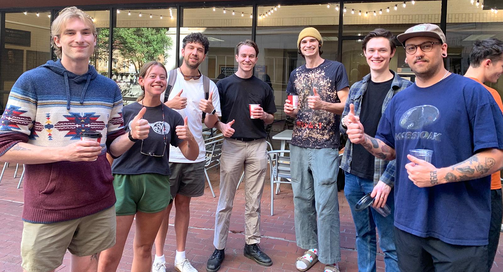 PharmTox graduate students standing in a group, drinking coffee and giving the 'thumbs up' sign