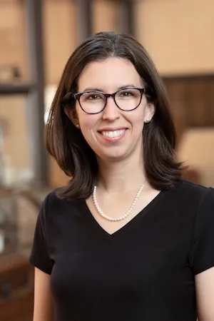 A woman wearing glasses and smiling.
