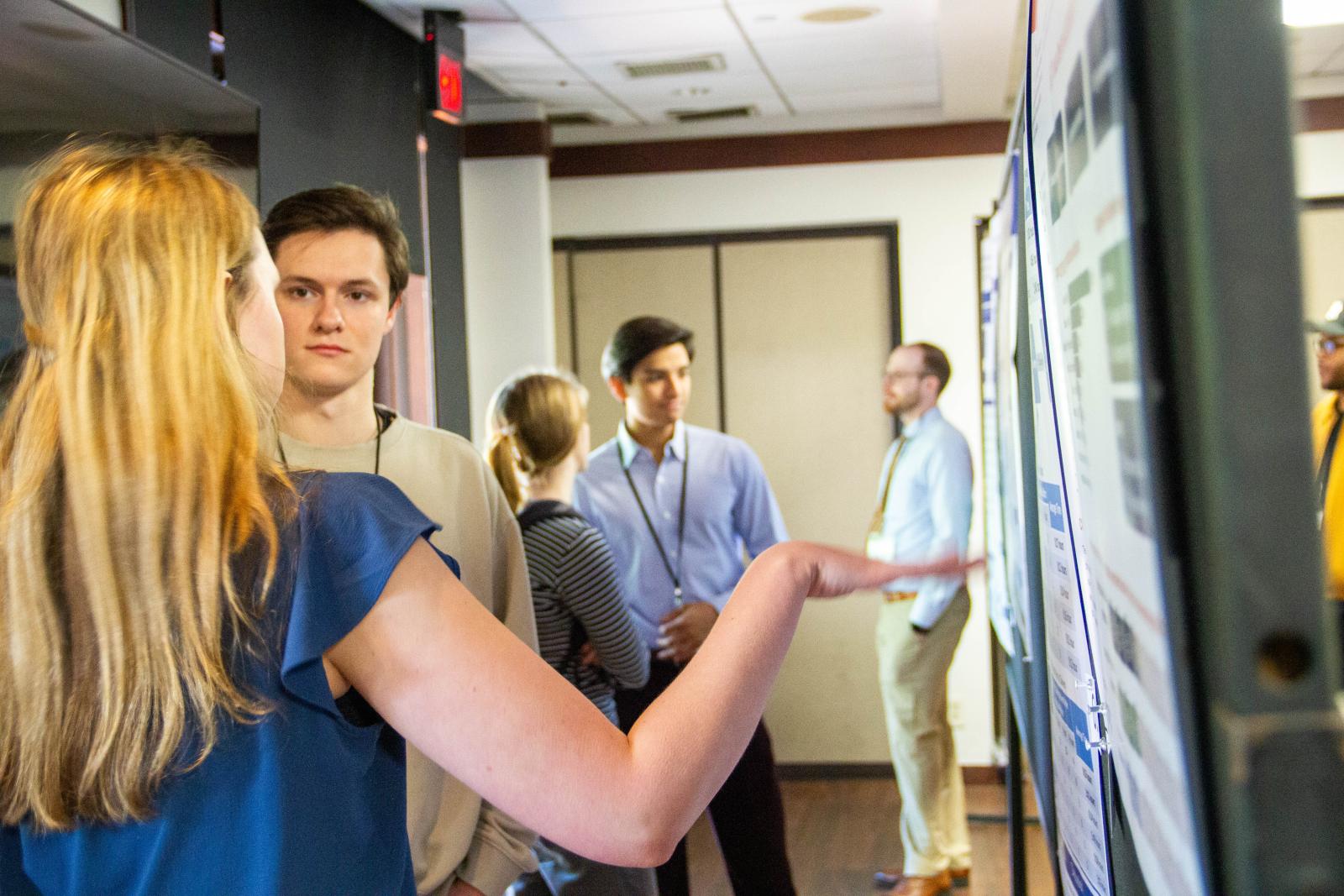 Someone presenting a research poster in a hallway.