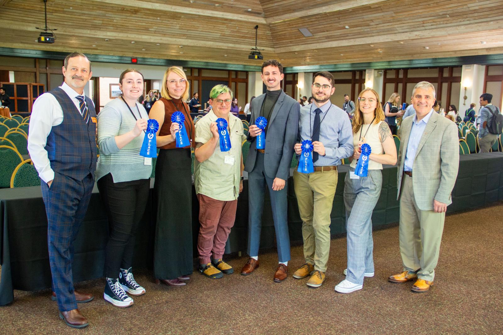 A group of people standing in a line holding award ribbons.