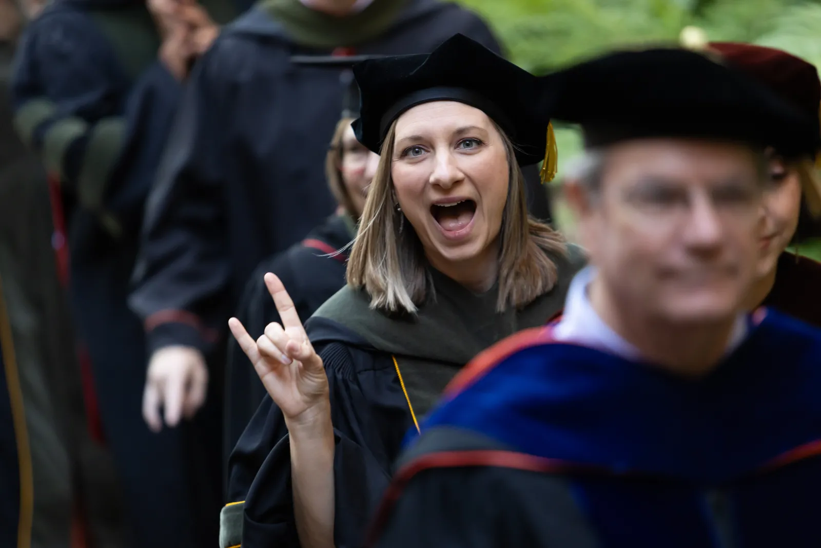A woman smiling and giving the Hook 'em.