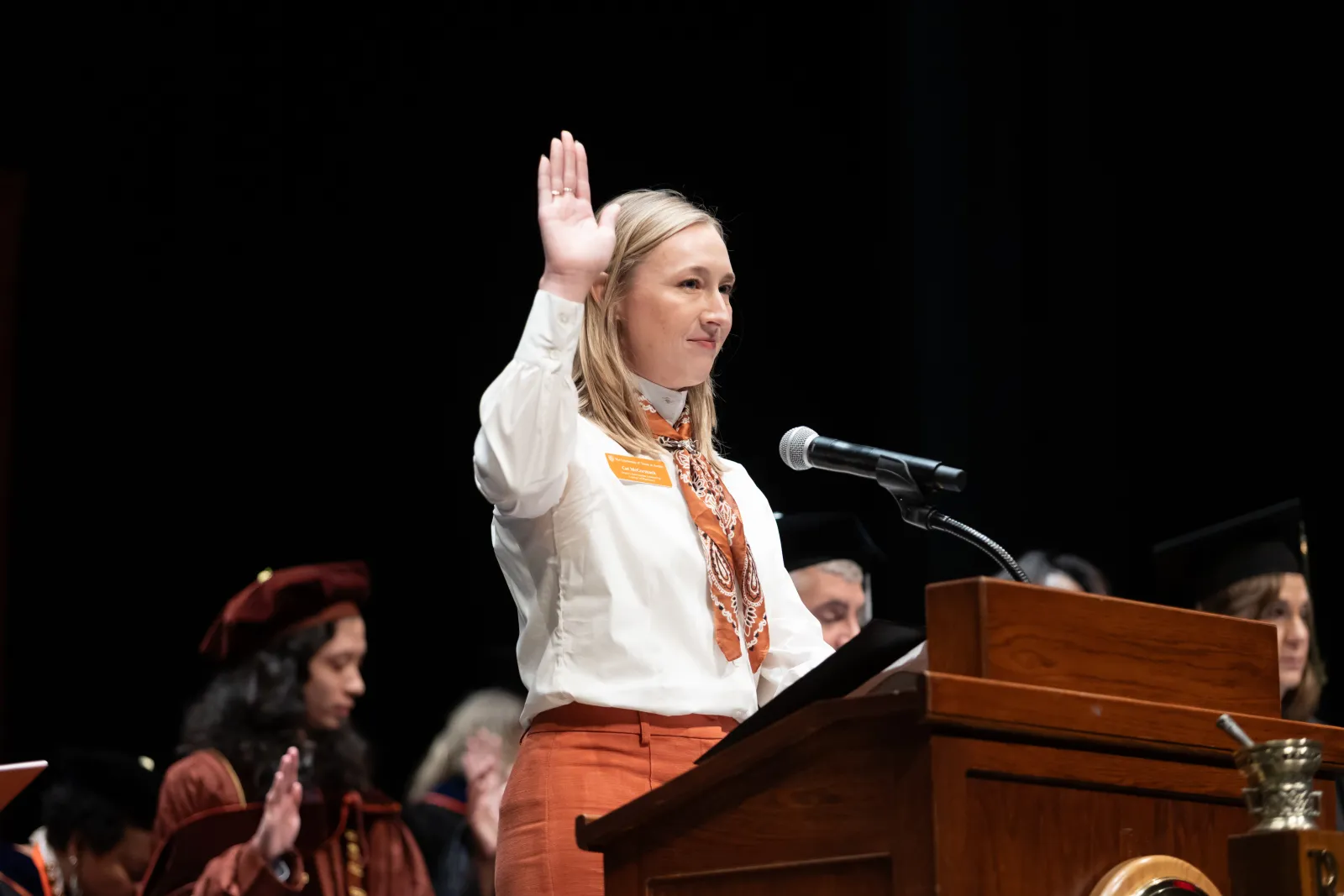 A woman holding her hand up to recite the Oath of a Pharmacist.