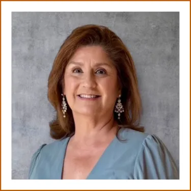 A headshot of Alma Gutierrez, UT Austin Pharmacy Alumna. Aluma is wearing a blue blouse, silver dangling earrings and is smiling to camera.