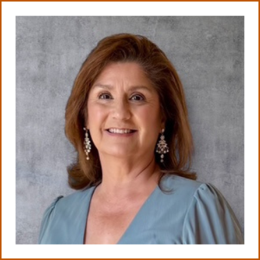 A headshot of Alma Gutierrez, UT Austin Pharmacy Alumna. Aluma is wearing a blue blouse, silver dangling earrings and is smiling to camera.