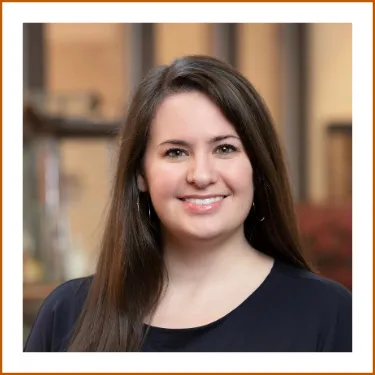 Headshot of Dr. Kristin Janzen. She has long brown hair, brown eyes and is wearing a dark top while smiling to camera.