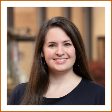 Headshot of Dr. Kristin Janzen. She has long brown hair, brown eyes and is wearing a dark top while smiling to camera.