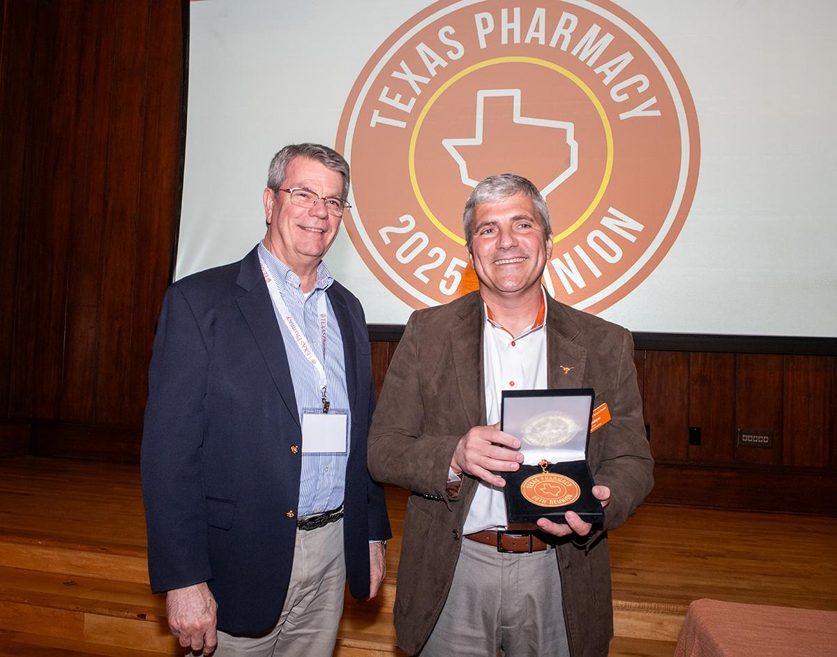 Dr. Ken Lawson and Dean Samuel Poloyac smiling at the 2025 reunion. Dean Poloyac is holding a medal in a black case.