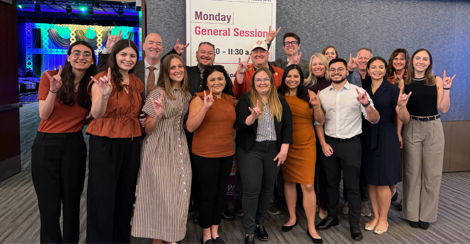 A group photo of Texas Pharmacy students, staff, faculty and alumni posing with the "hook 'em horns" hand gesture at a conference.