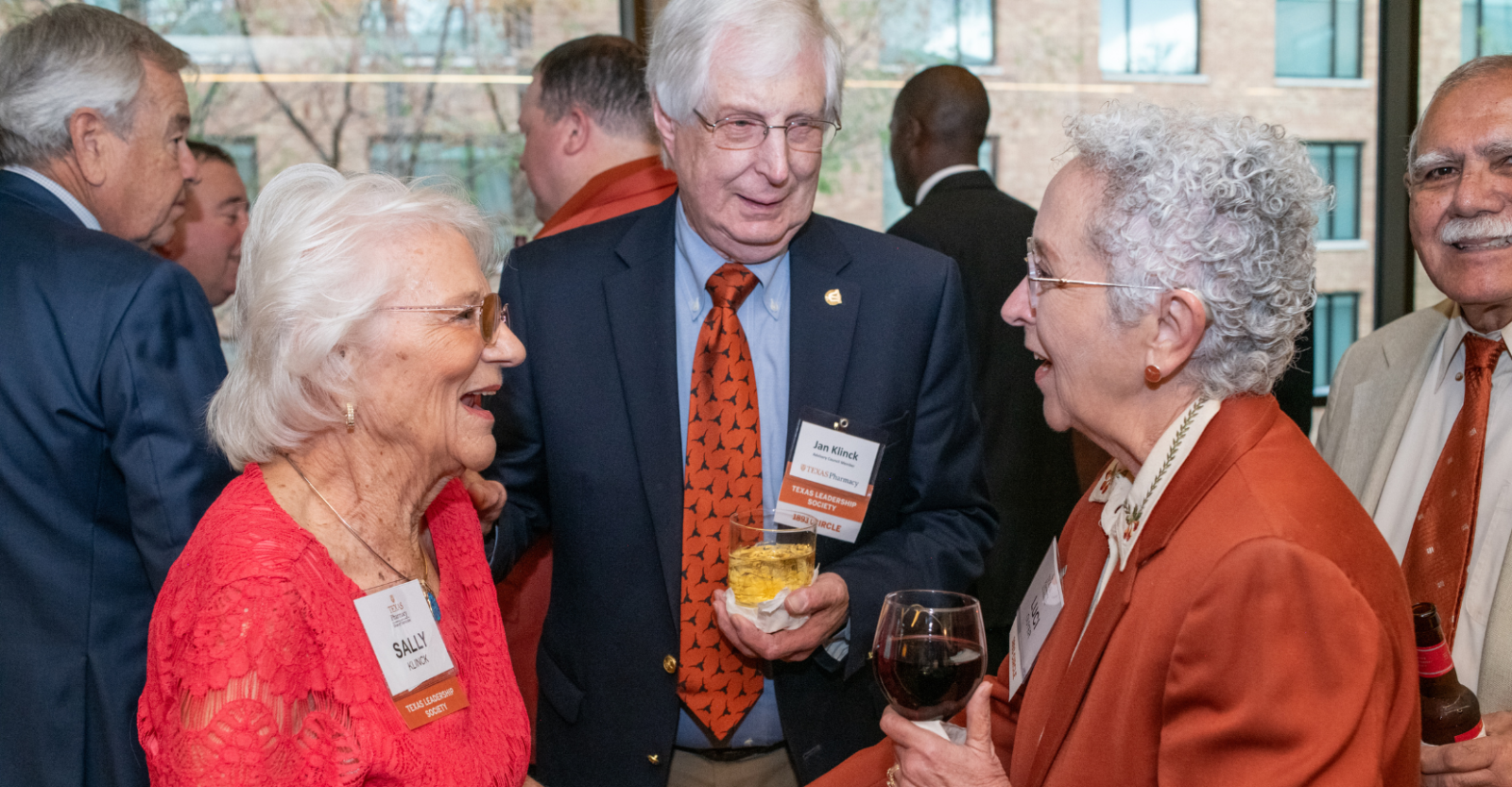 A group of older alumni chatting together at a lively reception.