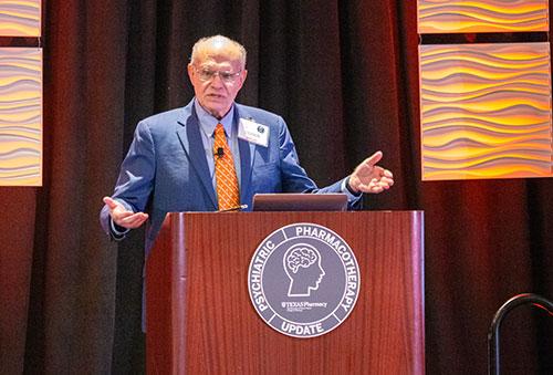 Dr. Saklad speaking at a podium with the Psychiatric Pharmacotherapy Update logo affixed to the podium