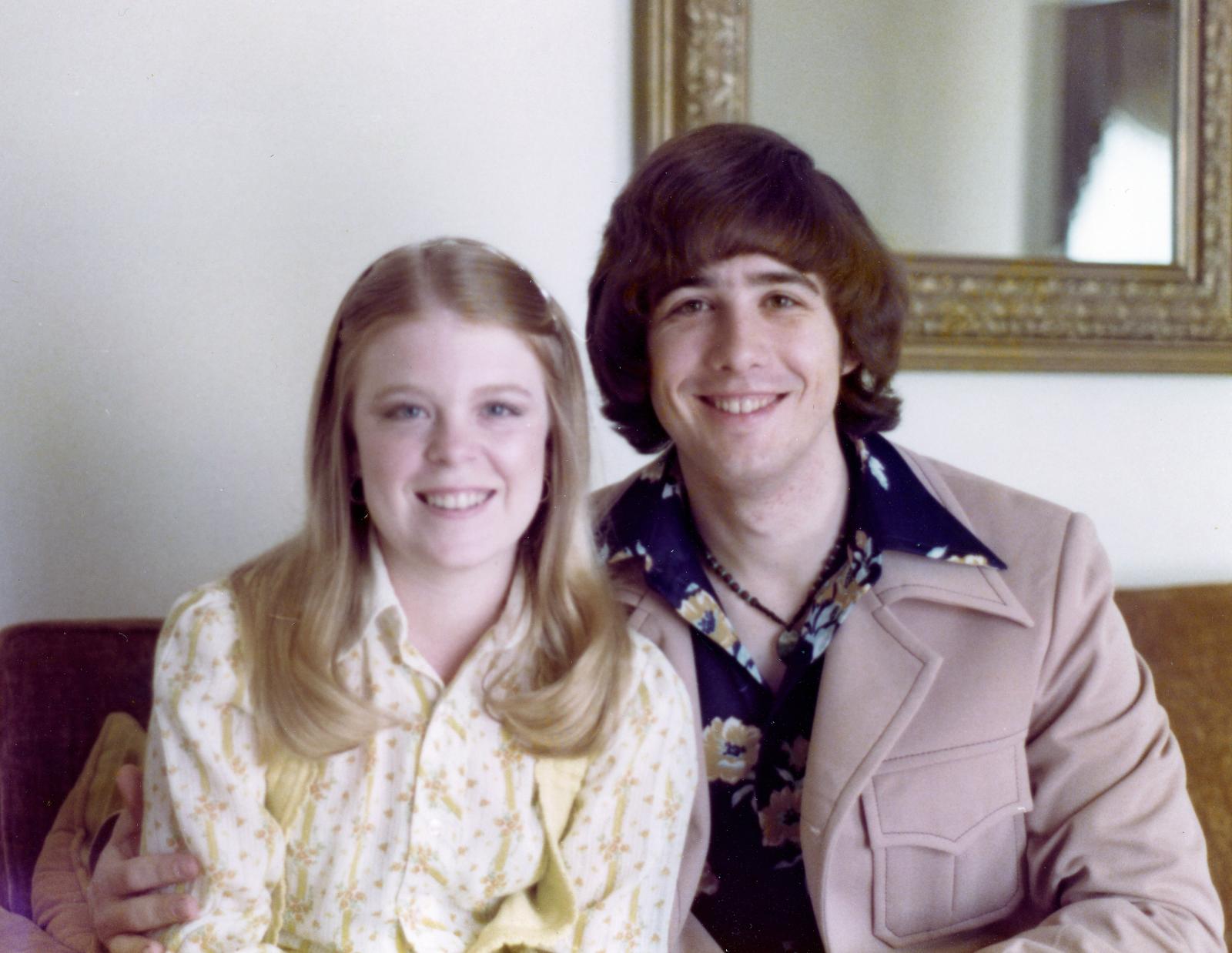 A photo of Annette and Wayne in 1976 - sitting together on the couch, smiling and celebrating their engagement.