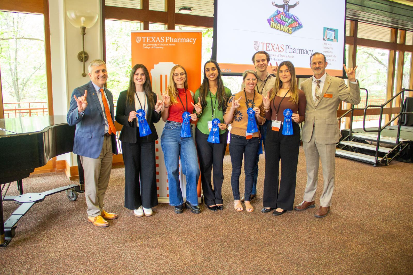 People holding up prize ribbons and giving the Hook 'em Horns hand gesture.