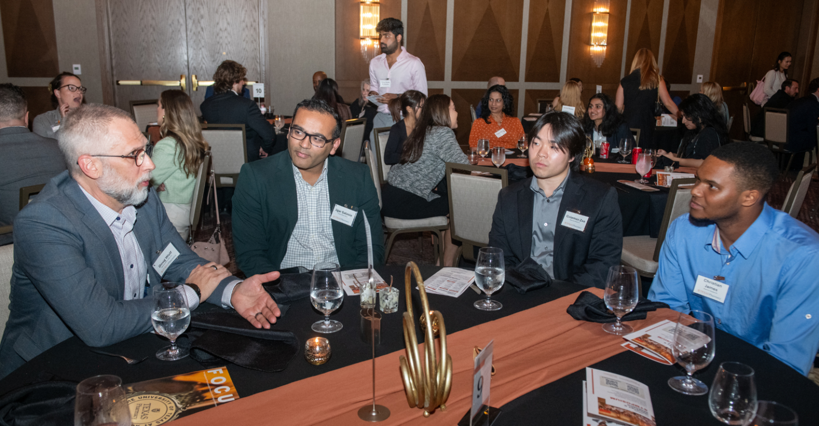 Four men sit together having a lively discussion at a professional networking event.