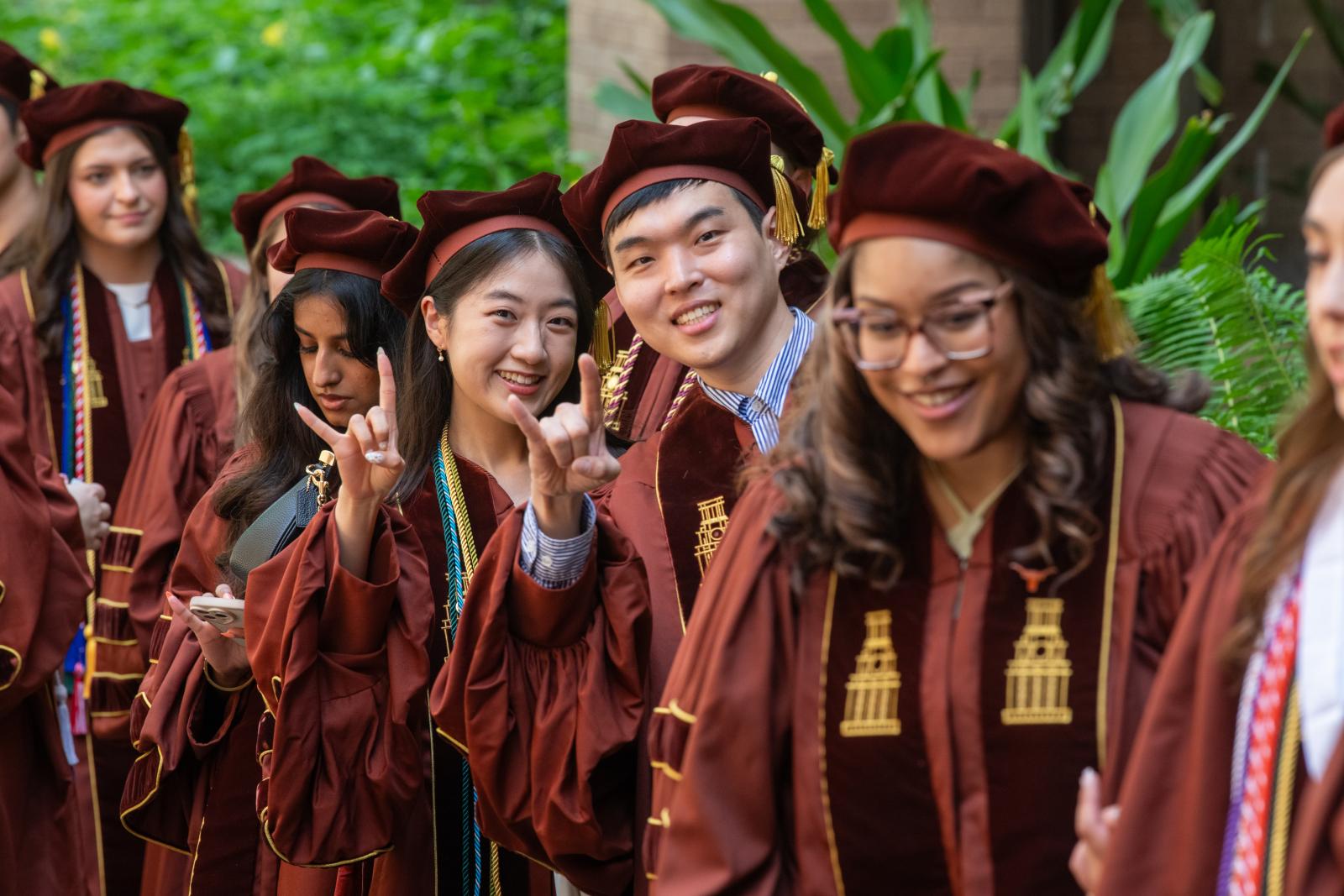Pharm.D. graduates in the processional giving the Hook 'em Horns hand gesture.