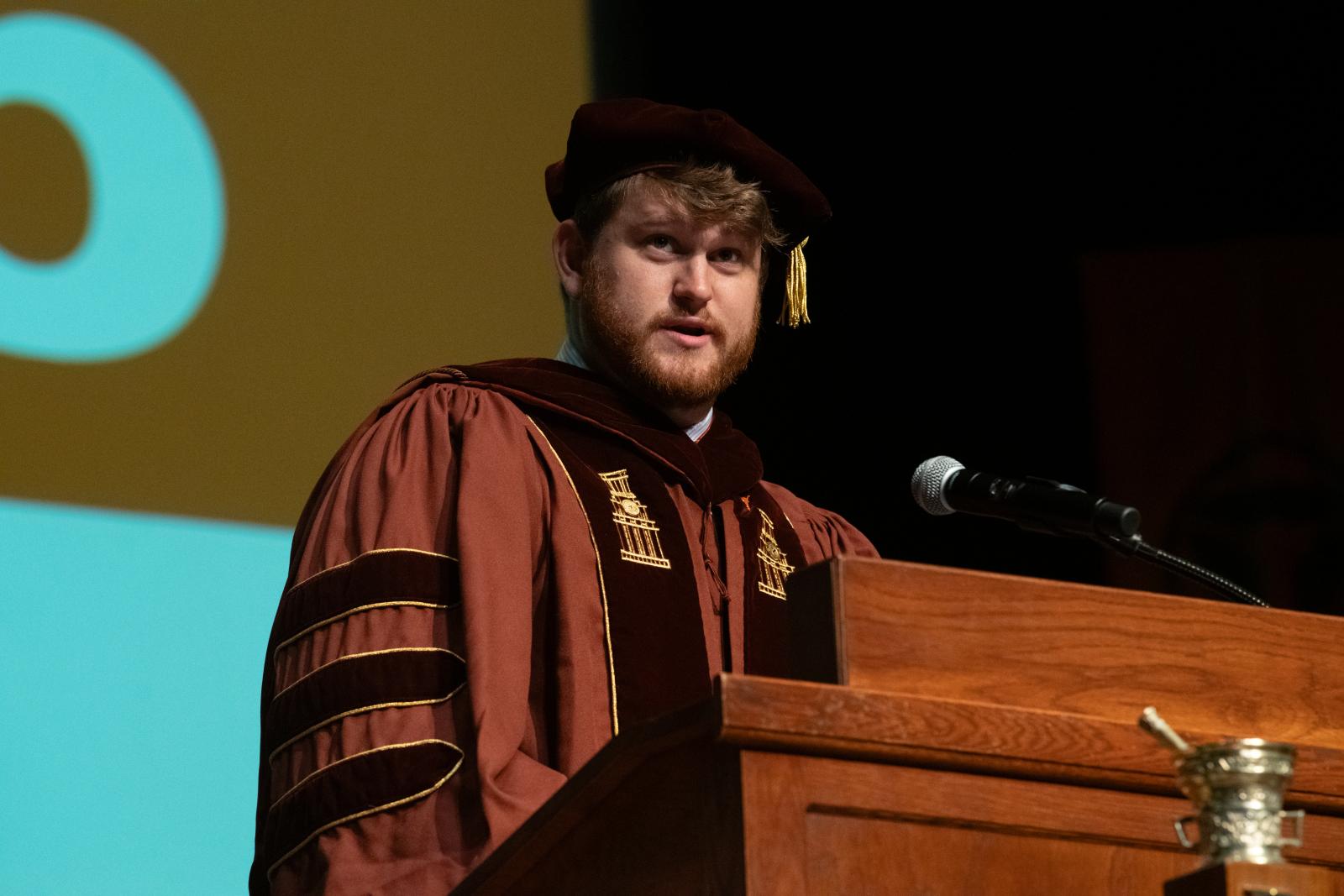 A man in graduation robes standing at a podium.