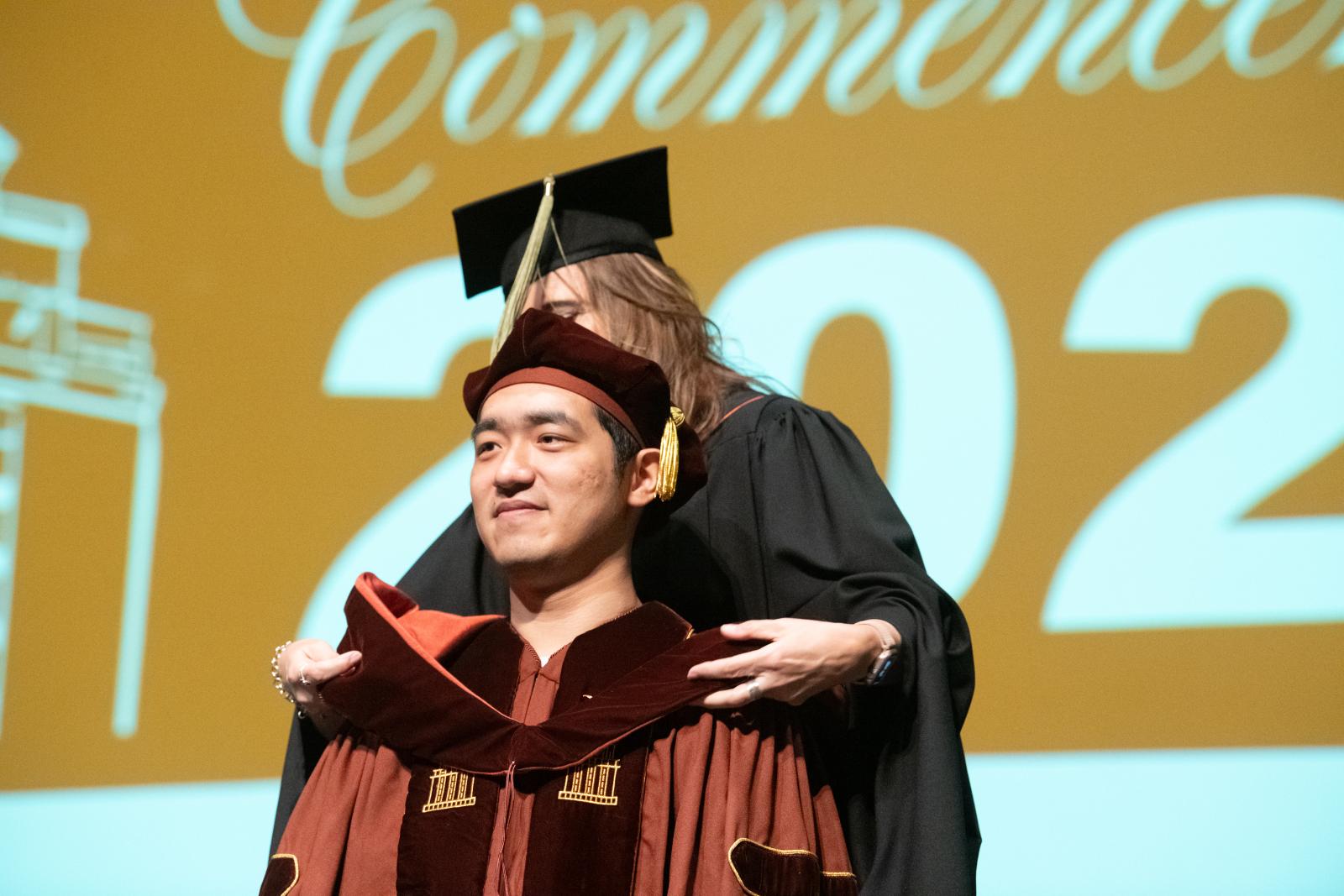 A Pharm.D. graduate being hooded on stage.