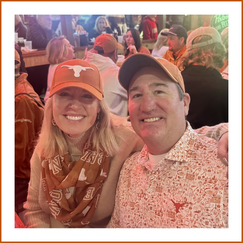 Rob and Ronna Hauser pose together at a UT Austin event wearing burnt orange gear.