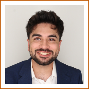 Headshot of student pharmacist Harris. Harris smiles brightly to camera in a navy jacket and white shirt. 