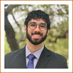 Headshot of student pharmacist Ryan. In front of a backdrop of trees and greenery, Ryan smiles brightly to camera in a grey suit with purple tie.