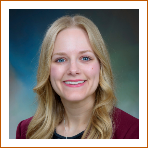 Headshot of a smiling blonde woman in a burgundy blazer.