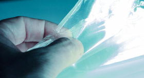A hand touching a transparent sheet.