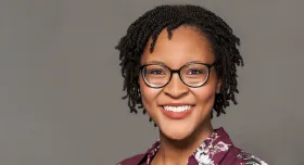 A woman wearing glasses and smiling.