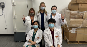 Five people in lab coats wearing masks.