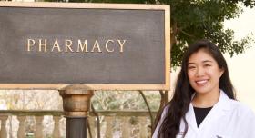 A woman smiling next to a sign that says "Pharmacy."