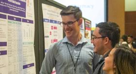 People standing in front of a research poster.