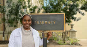Student pharmacist Amaka Epoh with the UT College of Pharmacy building sign.