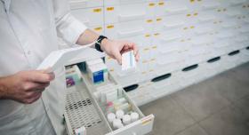 A pharmacist holding a box of medication.