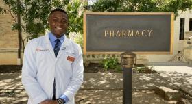 Student pharmacist Bruno Onwukwe standing in front of the Pharmacy sign on campus.
