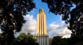 A tall clock tower with trees enveloping it in the foreground.