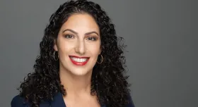 A woman smiling while wearing a blazer.