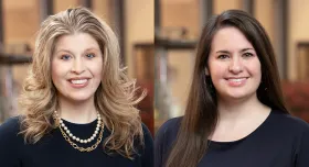 Two women smiling while both wear dark clothing.