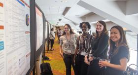 Texas Pharmacy faculty, student and staff standing near poster displays at Pharmacy Research Excellence Day.