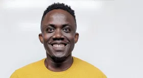 A man smiling and wearing a light sweater.