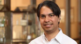 Dr. Mukhopadhyay wearing a collared shirt and smiling.