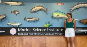 A woman standing in front of some mounted fish and a sign that says "Marine Science Institute."