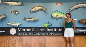 A woman standing in front of some mounted fish and a sign that says "Marine Science Institute."