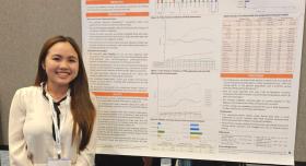 A woman standing in front of a research poster and smiling.
