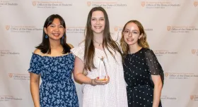 Three female members of the PPA Student Group pose together with a trophy.