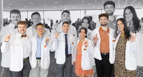 A group shot of Texas Pharmacy students at the white coat ceremony. They are holding up the "Hook 'em" hand gesture and smiling to camera.