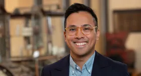 A man wearing glasses and smiling.