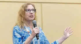 Dr. Andrea Gore holding a microphone and talking.