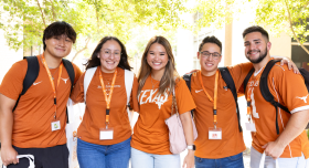 Five Texas Pharmacy students pose together, smiling brightly to camera wearing burnt orange t-shirts and lanyards.