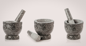 Three grey stone mortar and pestles on display against a cream background.