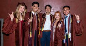A group of Pharm.D. graduates giving the Hook 'em Horns hand gesture.