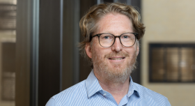 Landscape professional image of Dr. Smyth with glasses and a blue shirt.