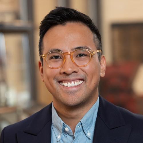 Dr. Anton Avancena wearing a suit jacket and glasses and smiling.